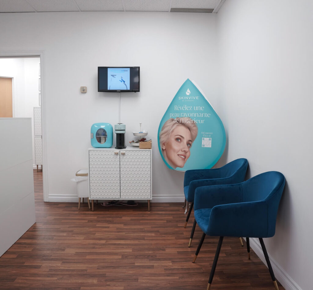 Coin détente de la clinique avec deux fauteuils bleus, une station café et une affiche promotionnelle Skinvive