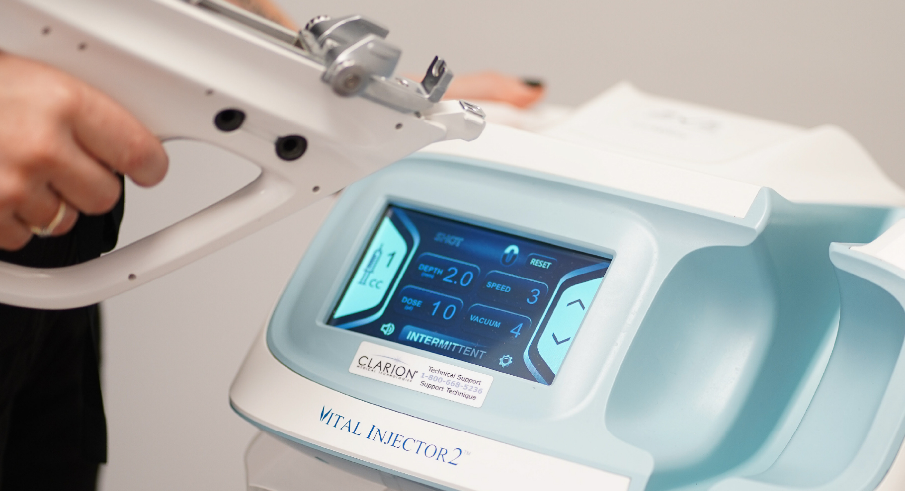 Appareil Vital Injector 2 utilisé pour le traitement Beauty Booster, avec écran tactile affichant les réglages d’injection et main tenant la pièce à main.