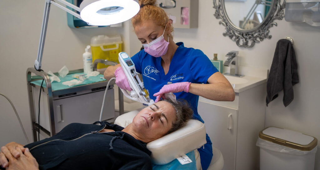 Traitement médico-esthétique du visage avec le Vital Injector 2 à la Clinique CGM, réalisé par une professionnelle portant un uniforme bleu et des gants roses