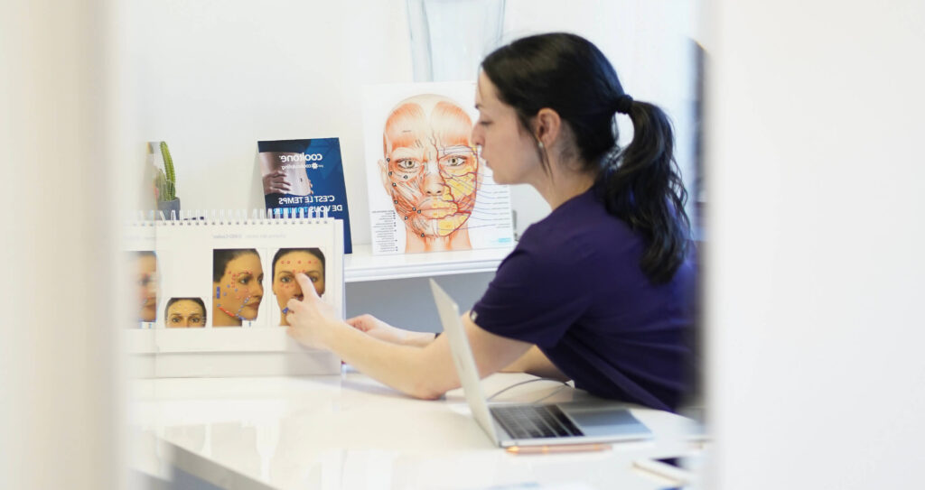Formation en anatomie faciale : professionnelle en clinique médico-esthétique expliquant les points d’injection à l’aide de visuels anatomiques.